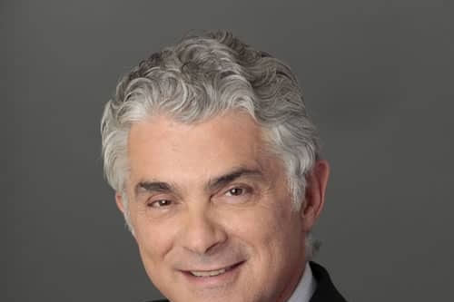 Dr. Carlos Wolf in a dark suit and pink tie